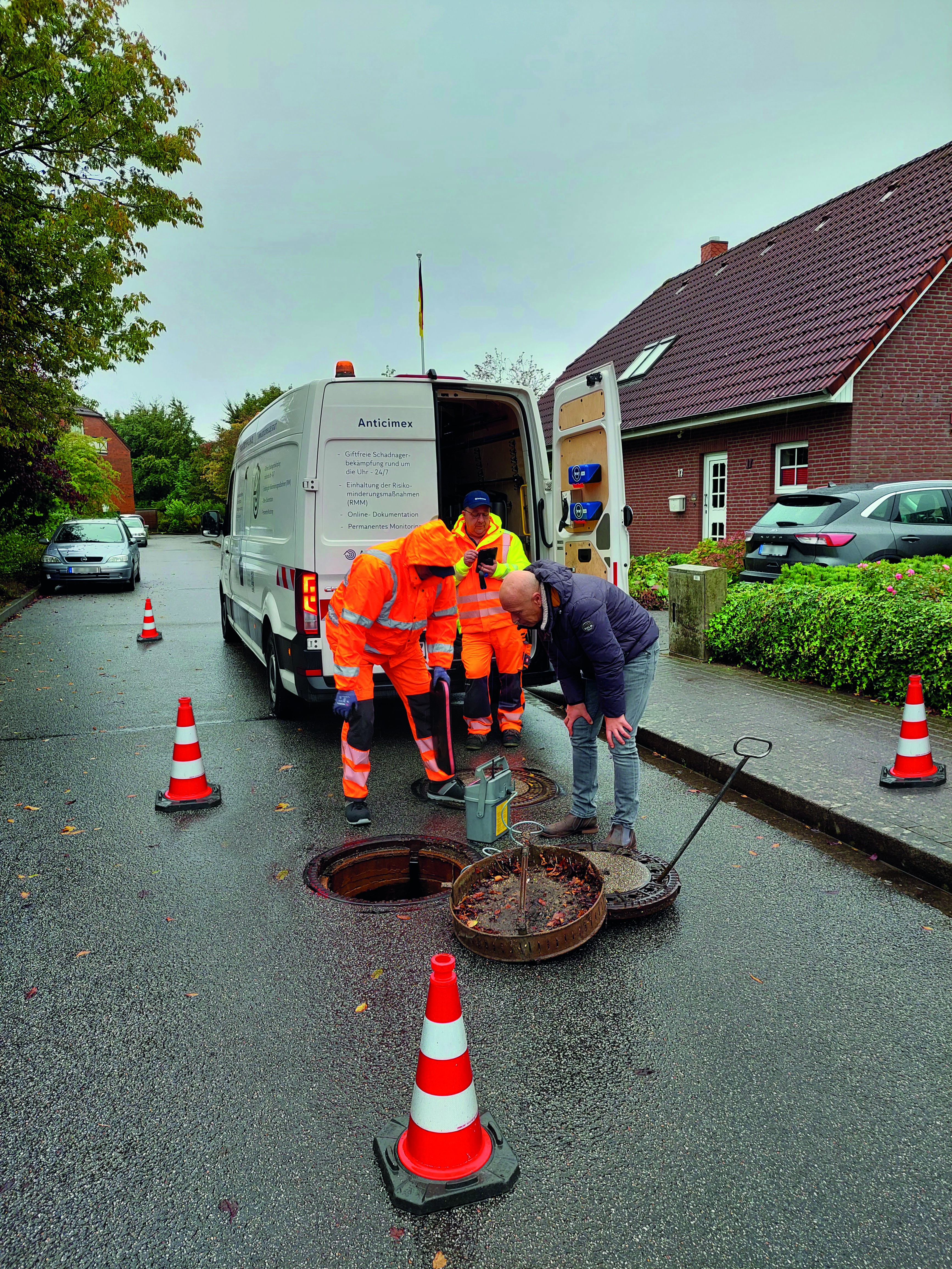 Ein Kanaltrupp installiert eine smarte Schlagfalle in einem Kanaltschacht 